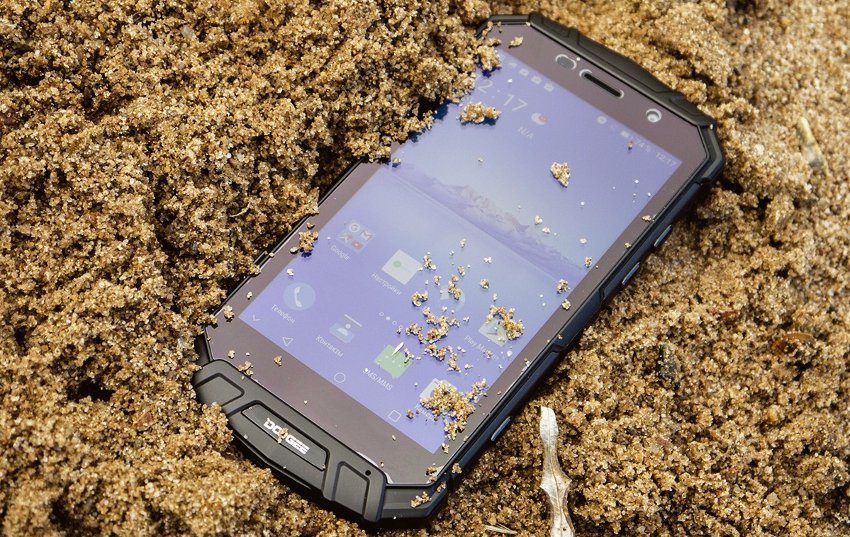 защищенный смартфон в песке