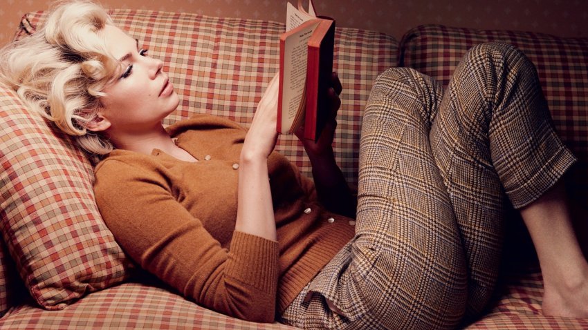 Женщина читает книгу лежа на диване